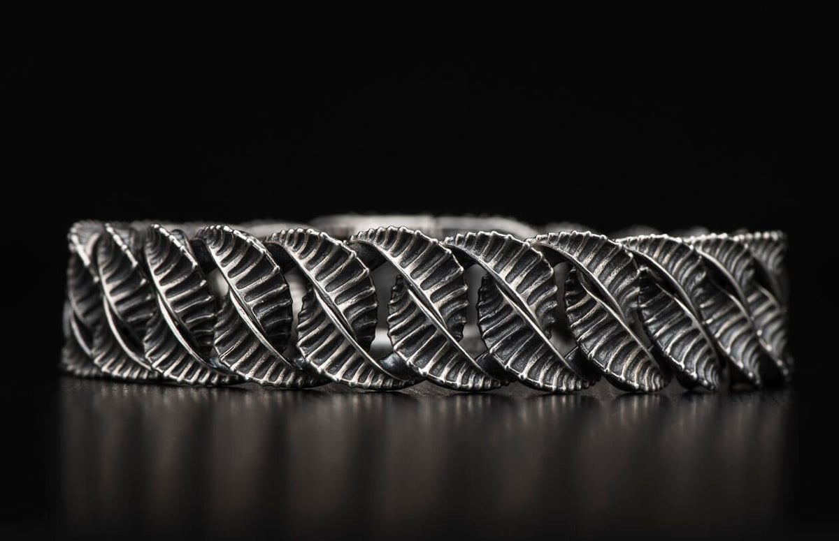 Oxidized silver metal bracelet with interlocking textured leaf-like segments.