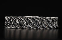 Oxidized silver metal bracelet with interlocking textured leaf-like segments.