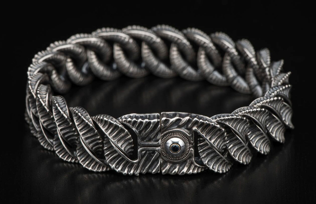 Oxidized silver bracelet featuring intricate leaf-like links and a central black gemstone on the decorative clasp.