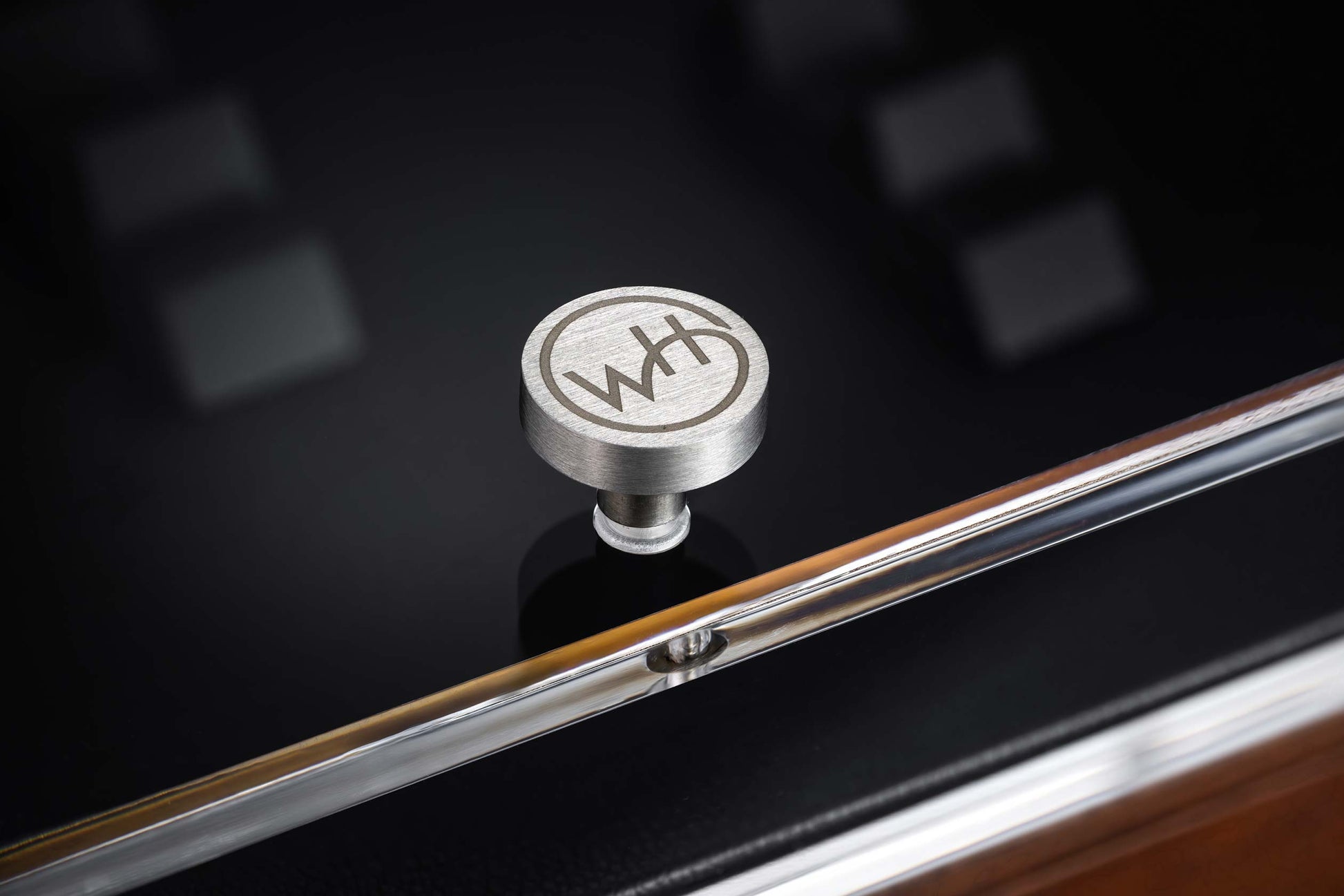 Metal knob with a WH logo on a reflective surface