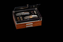 Set of knives in a wooden display case on a black background