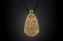 Bronze pendant with ornate floral and scrollwork designs, featuring dark accents, hanging on a black cord.