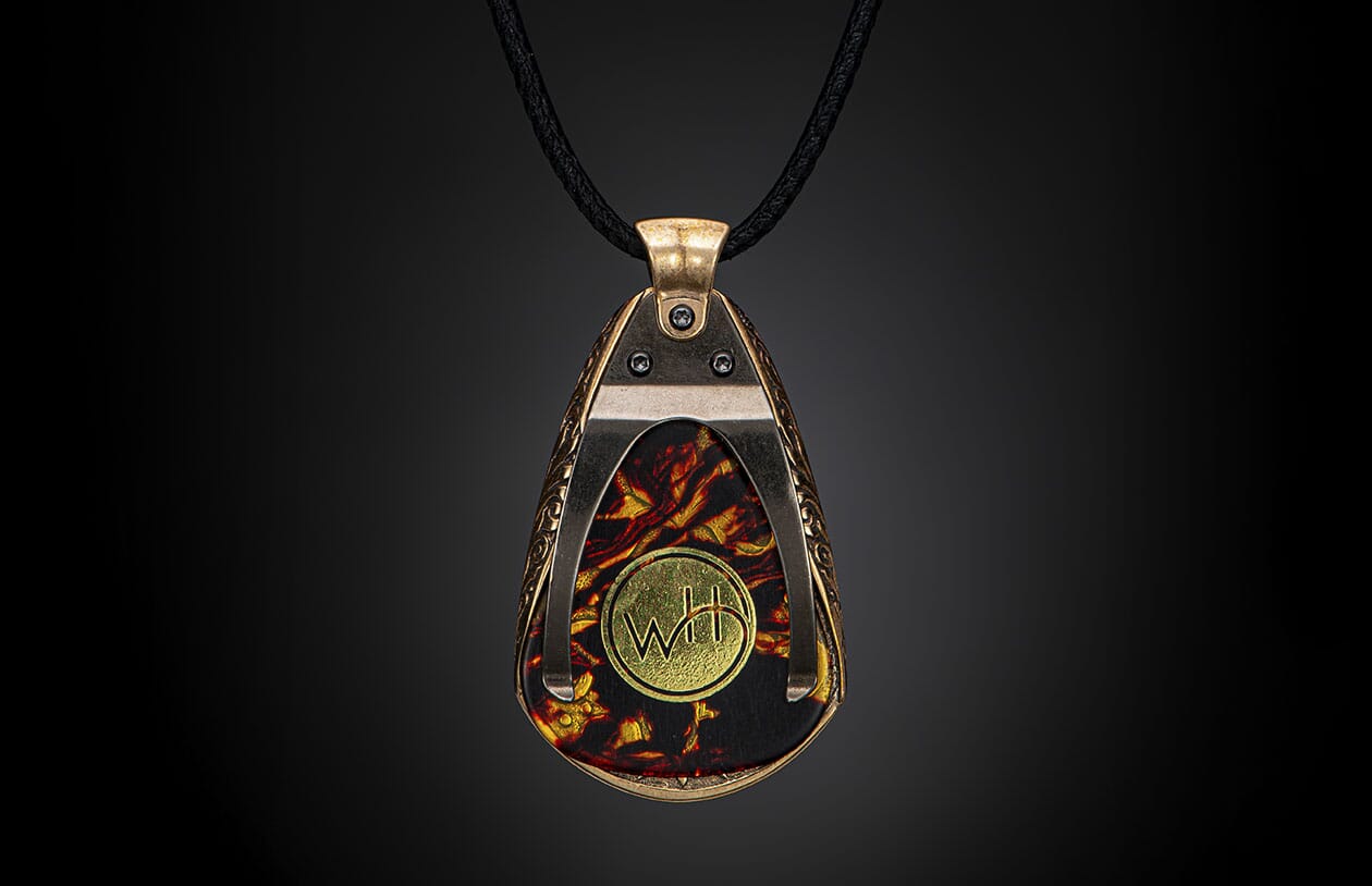 Bronze-toned pendant with a fiery red and gold marbled pattern, featuring a gold "WH" emblem, ornate frame, and black cord.