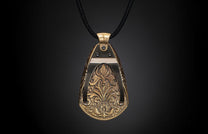 Ornate metallic bronze pendant with intricate floral and scrollwork relief, suspended from a black braided cord.