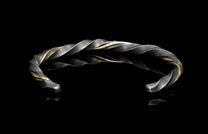 Twisted silver and gold bracelet on a black background