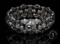 Intricate silver-toned bracelet featuring sculptural, mechanical designs and a central dark accent.