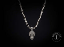 Intricate silver skull pendant necklace with dark eyes on a thick box chain, hanging vertically.