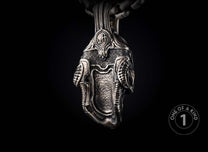 Intricate silver pendant with textured surface, featuring a central panel, ridged sides, and a 'WH' emblem.