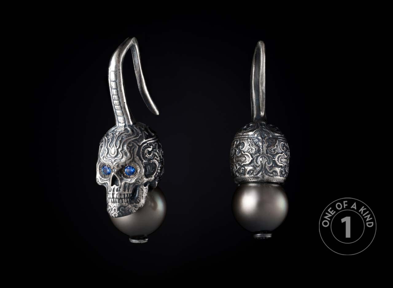 Pair of ornate silver skull earrings with blue gem eyes and black pearls, front and back views.