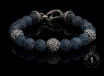 Sterling silver beaded bracelet with dark blue crackle agate beads and ornate silver accent beads, on a reflective surface.