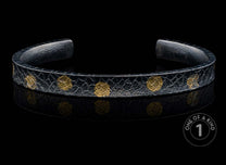 Black textured cuff bracelet with scattered gold-colored organic patterns.