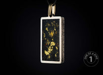 Rectangular silver-toned pendant with a dark center filled with glistening gold flakes, featuring textured sides and a gold bail, suspended against a black background.