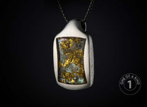 Textured silver-tone pendant with gold flakes embedded in light blue resin, hanging from a dark chain.