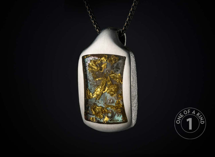 Textured silver-tone pendant with gold flakes embedded in light blue resin, hanging from a dark chain.