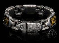 Chunky silver-colored bracelet with pebbled texture, featuring gold flake inlays and a unique clasp with an emblem.
