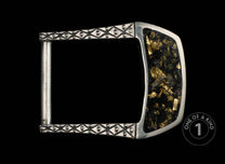 Silver metal belt buckle with black and gold flake inlay, featuring an ornate diamond pattern and 'one of a kind' mark.