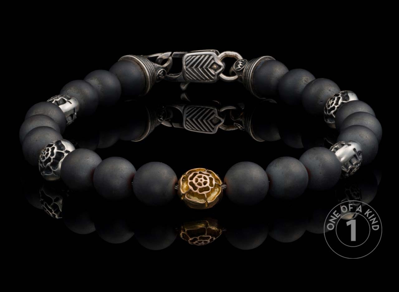 Matte black beaded bracelet with ornate silver-toned and gold-toned rose spacer beads, featuring a patterned silver clasp.