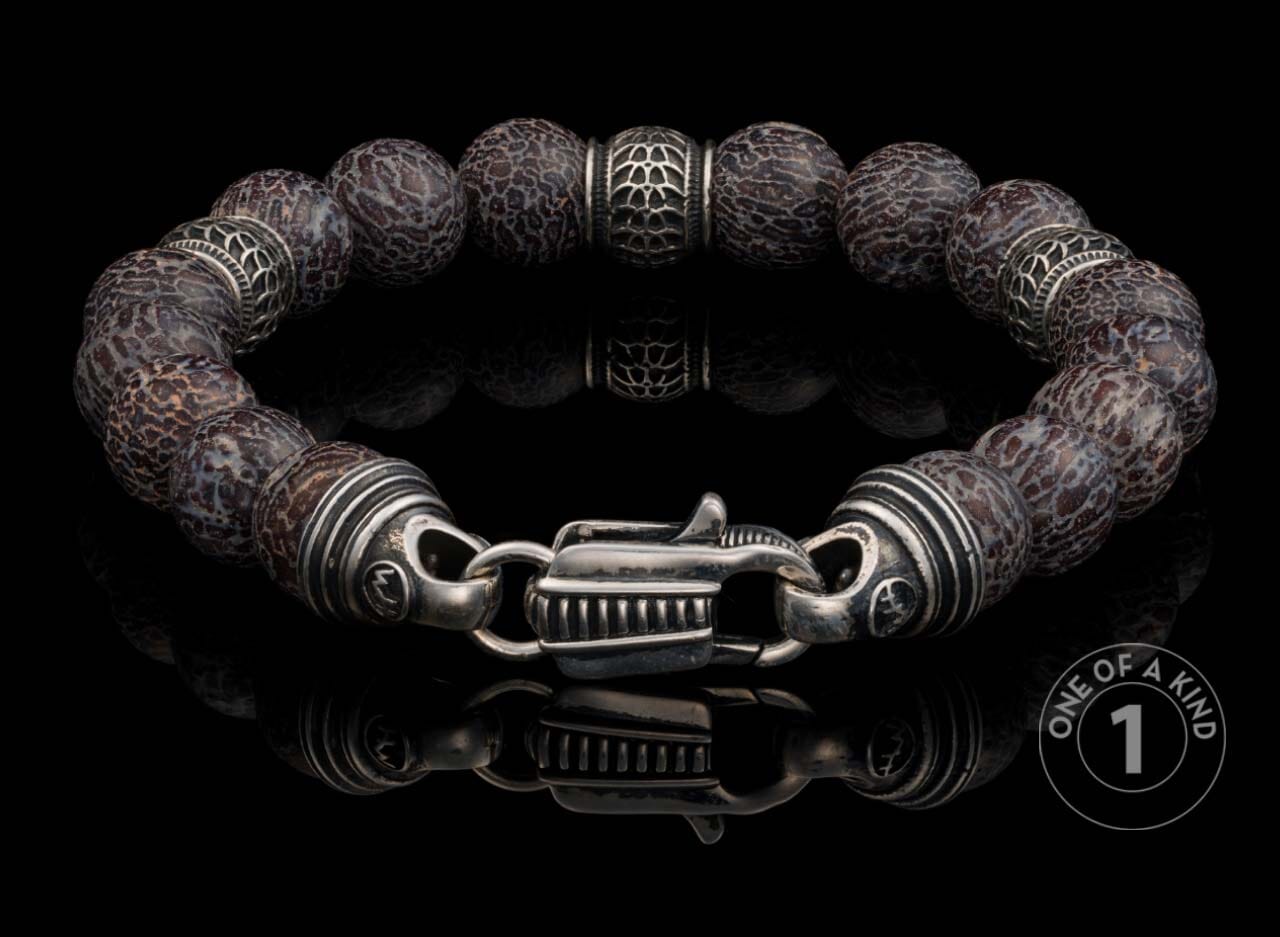 Beaded bracelet featuring dark grey patterned stone beads, decorative silver-toned spacers, and a unique clasp on black.