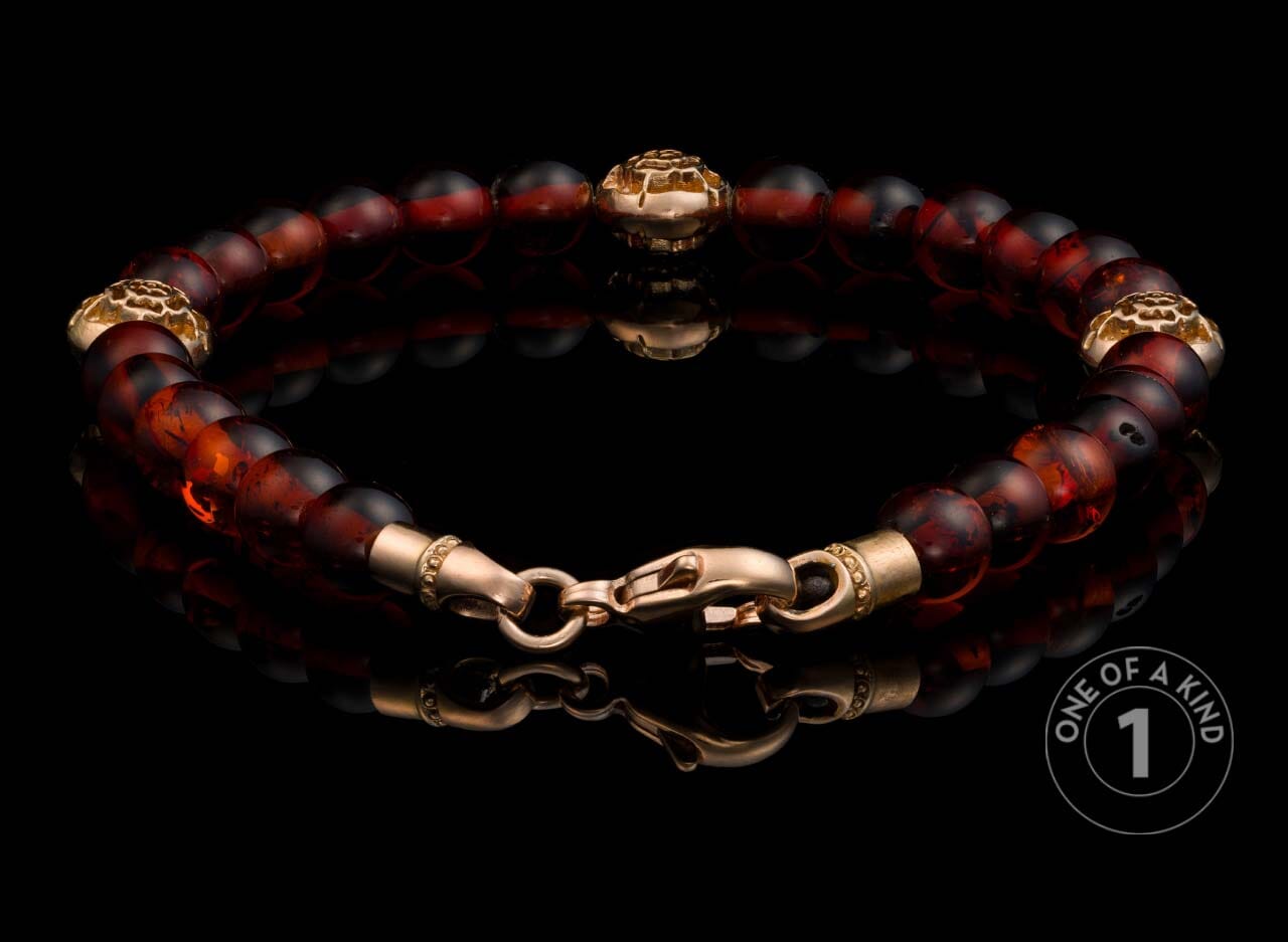 Dark red and brown beaded bracelet with ornate gold-tone metal spacer beads and lobster clasp.
