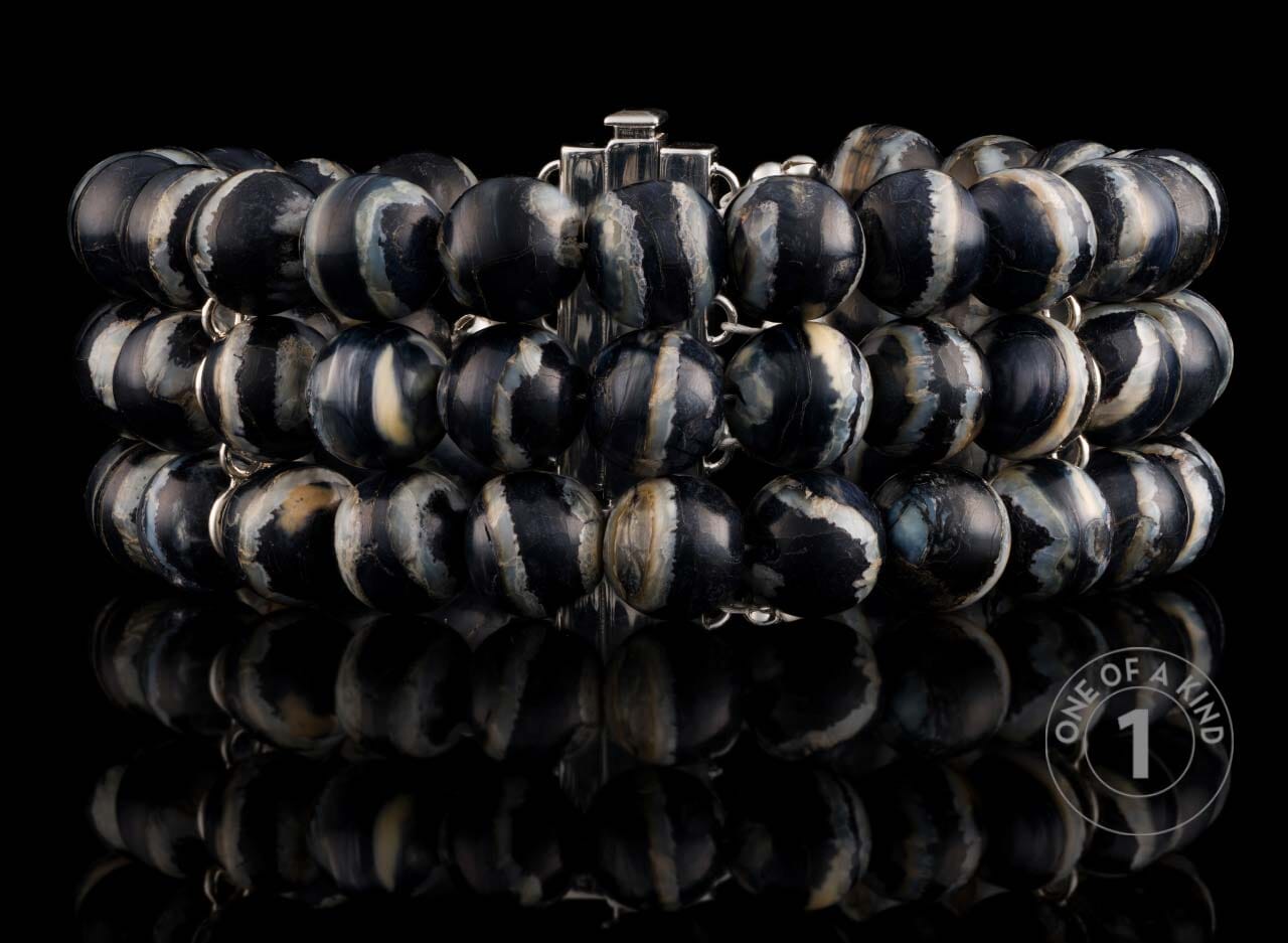 Chunky multi-strand bracelet with polished black and white marbled beads and silver-toned links, displayed with reflection.