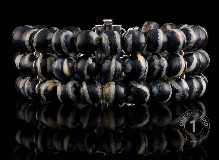 Chunky multi-strand bracelet with polished black and white marbled beads and silver-toned links, displayed with reflection.