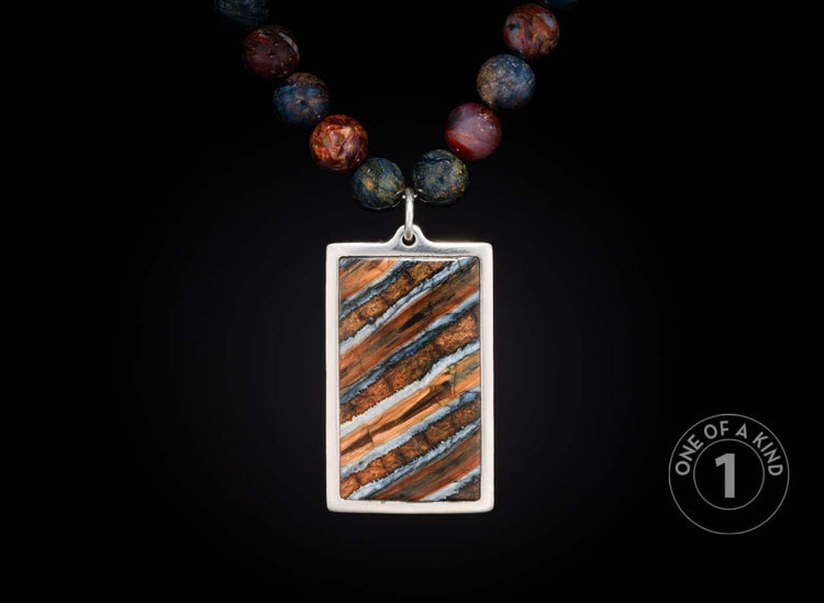 Silver-framed rectangular pendant necklace with orange, blue, and white striped stone on a string of mottled round beads.