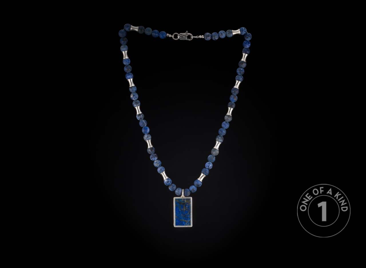 Blue beaded necklace with silver spacers, a silver clasp, and a rectangular blue stone pendant in a silver frame.