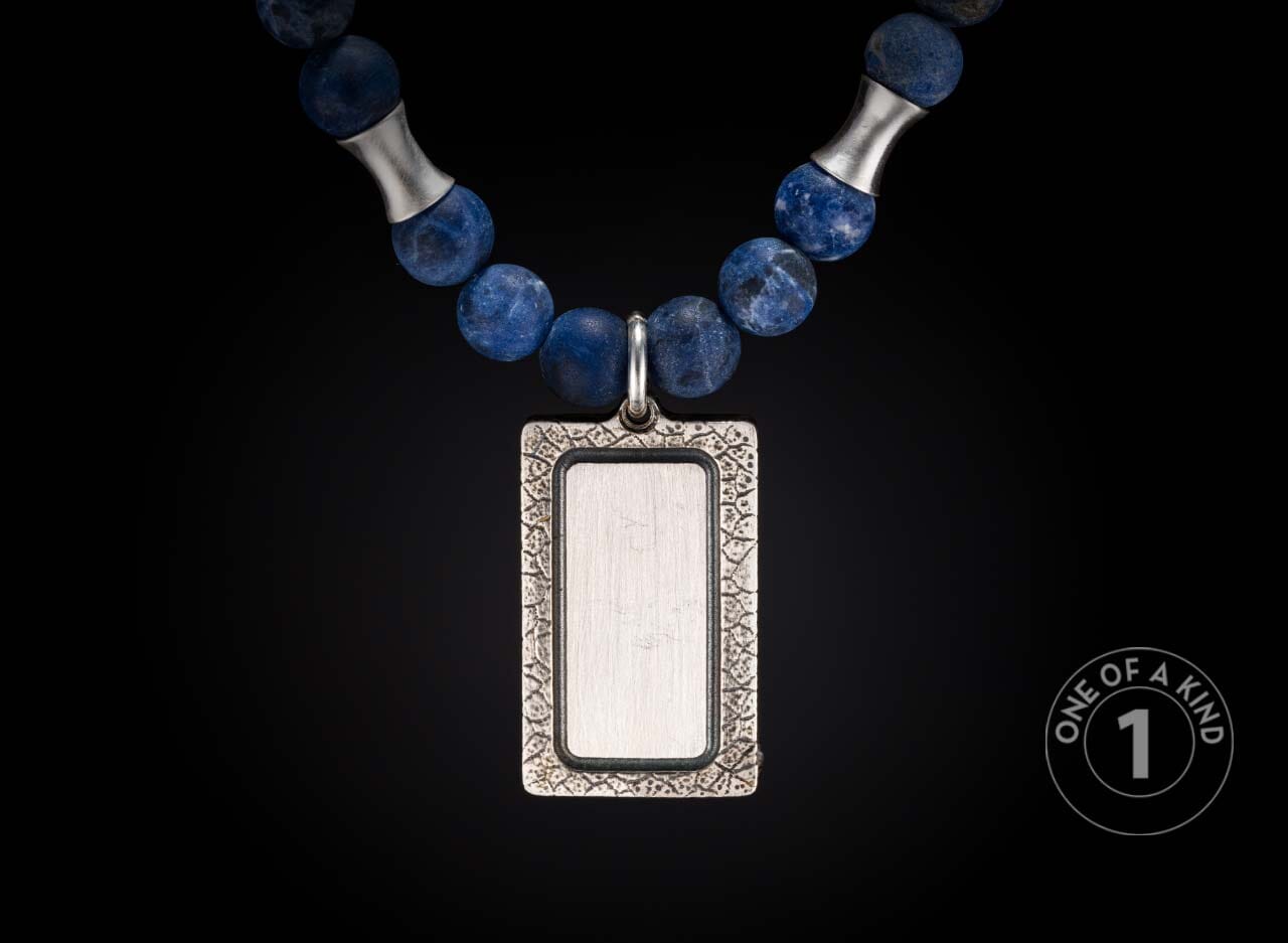 Blue stone beaded necklace with a rectangular silver pendant, an etched frame, and hourglass silver spacers.