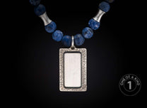 Blue stone beaded necklace with a rectangular silver pendant, an etched frame, and hourglass silver spacers.