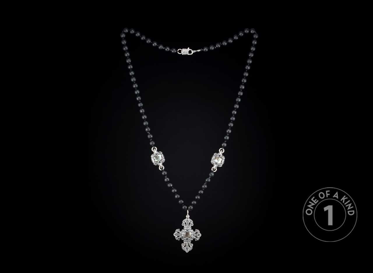 Black beaded necklace featuring a detailed silver-toned cross pendant and two decorative metal connectors.