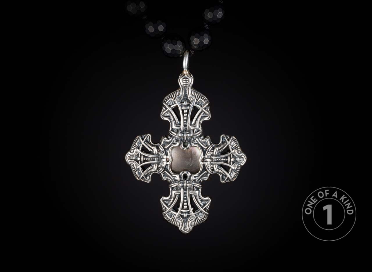 Ornate silver cross pendant with a central element, hanging from a black faceted beaded necklace.