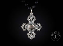Ornate silver cross pendant with a central element, hanging from a black faceted beaded necklace.