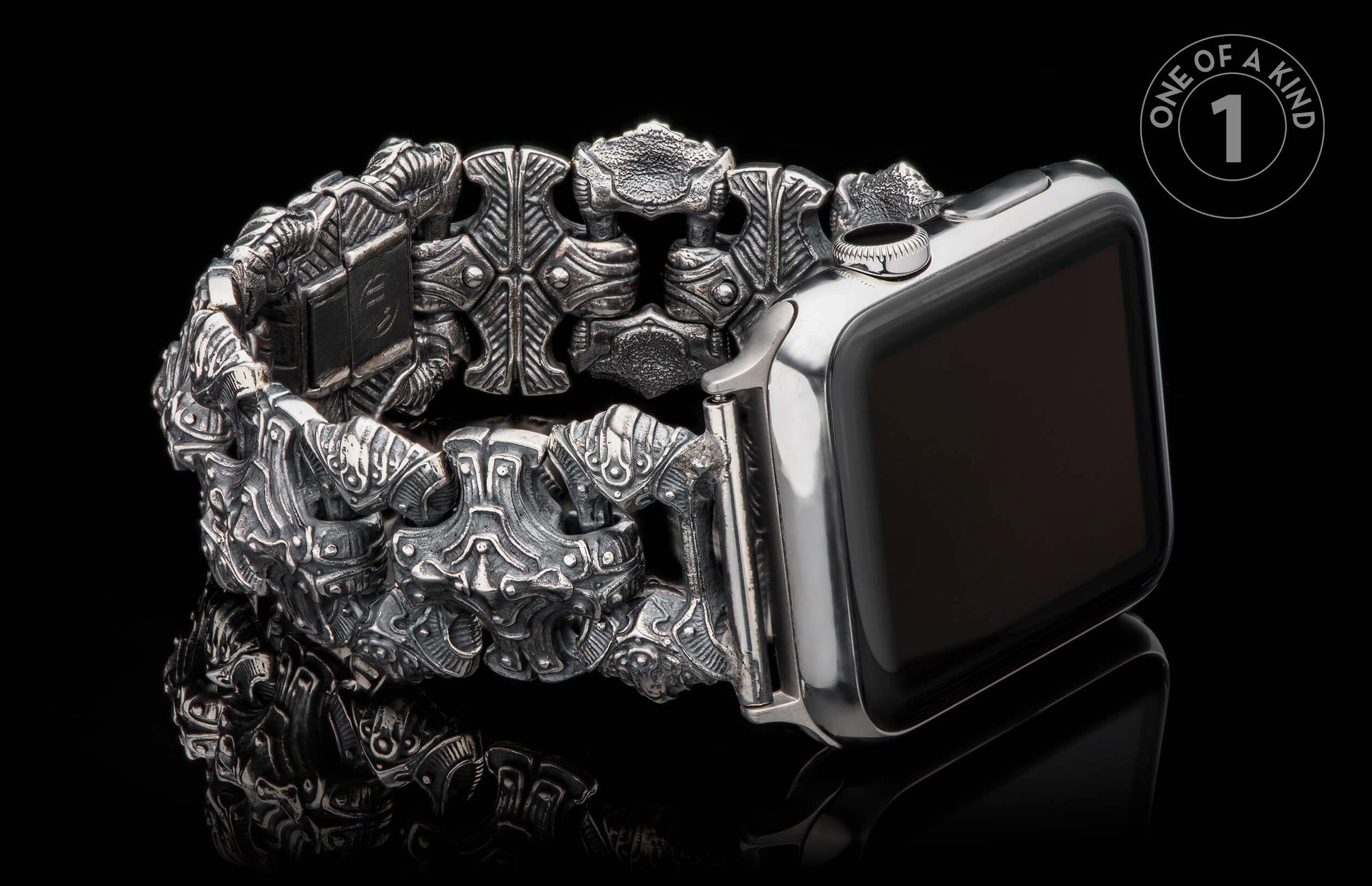 Ornate carved metal watch band with intricate links and a darkened silver finish, attached to a silver smartwatch.