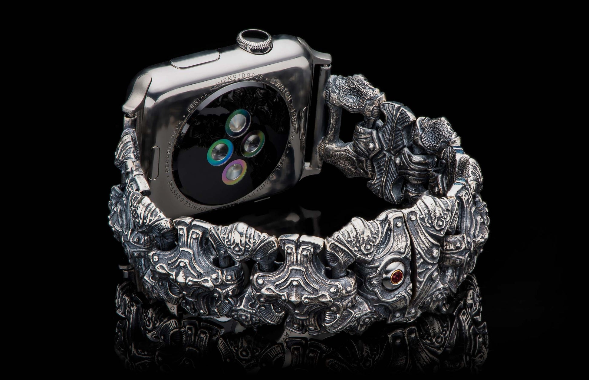 Ornate, sculpted dark silver metal watch band with intricate patterns and a red gemstone, attached to a smartwatch.