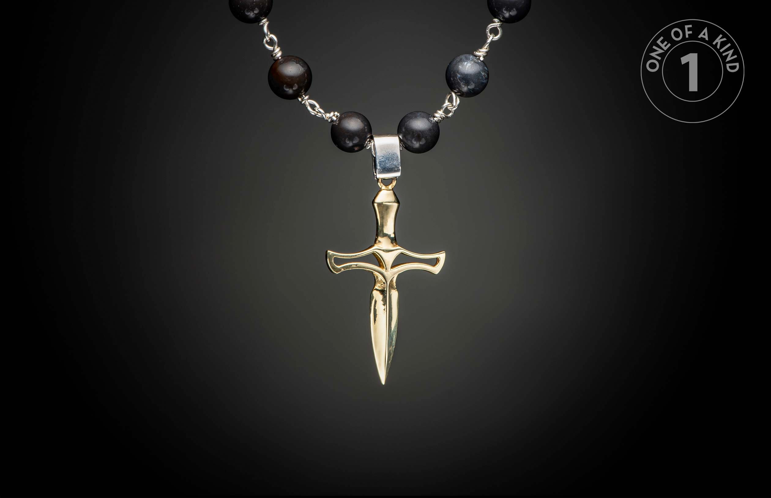 Gold-toned dagger pendant on a dark beaded necklace with silver wire connections.