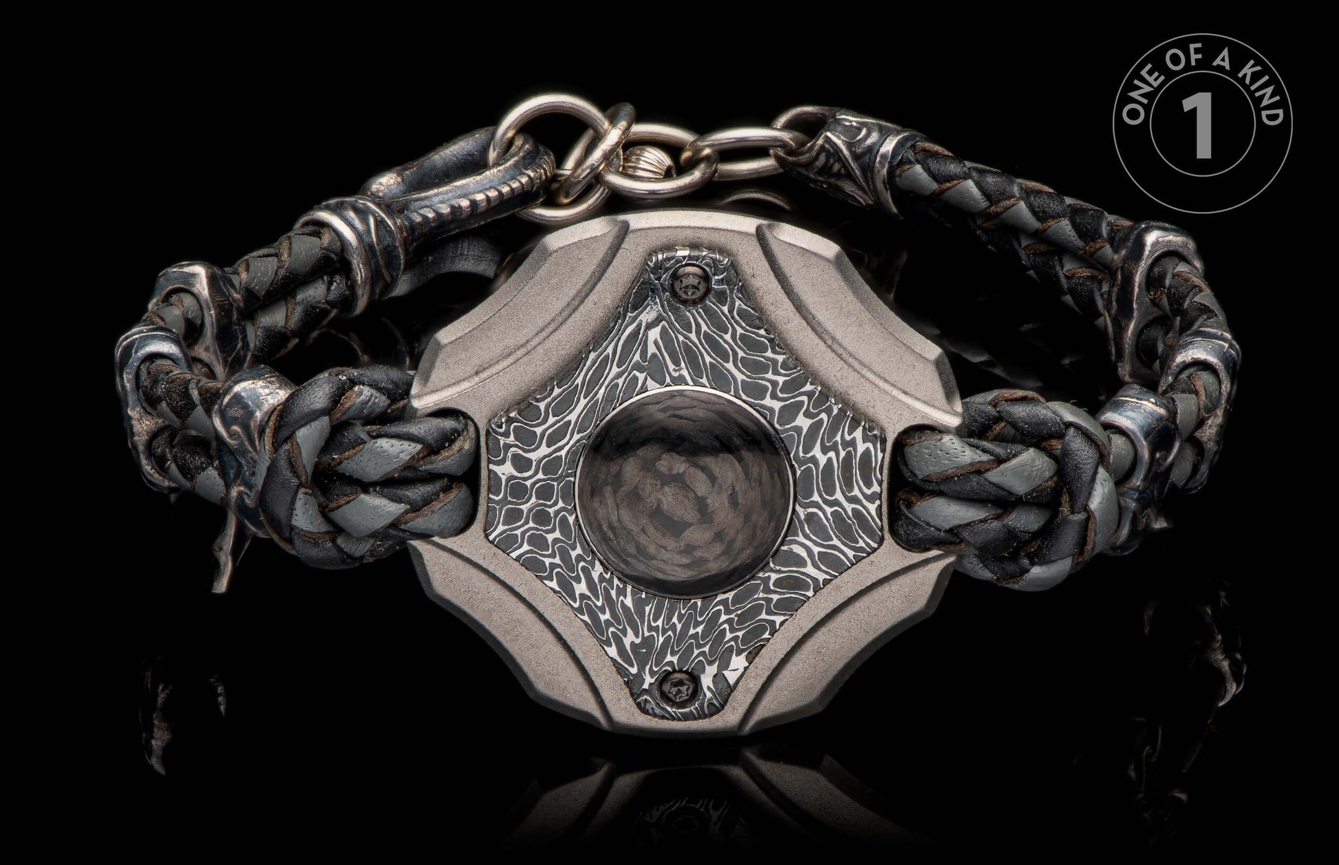 Front view of a braided black and grey leather bracelet with a textured grey metal centerpiece and a dark circular inlay.