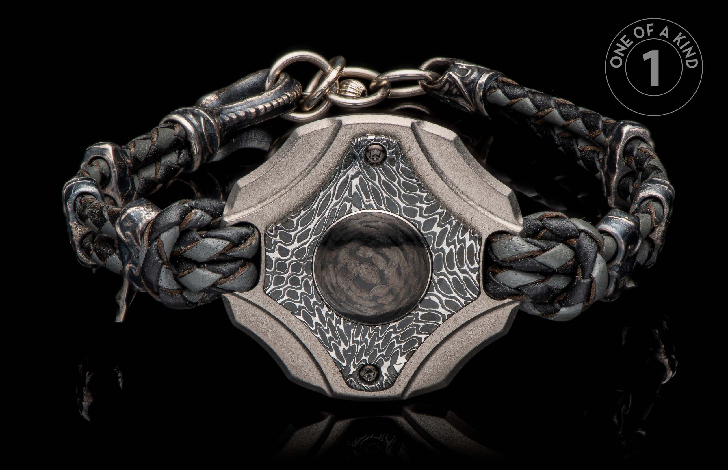 Front view of a braided black and grey leather bracelet with a textured grey metal centerpiece and a dark circular inlay.