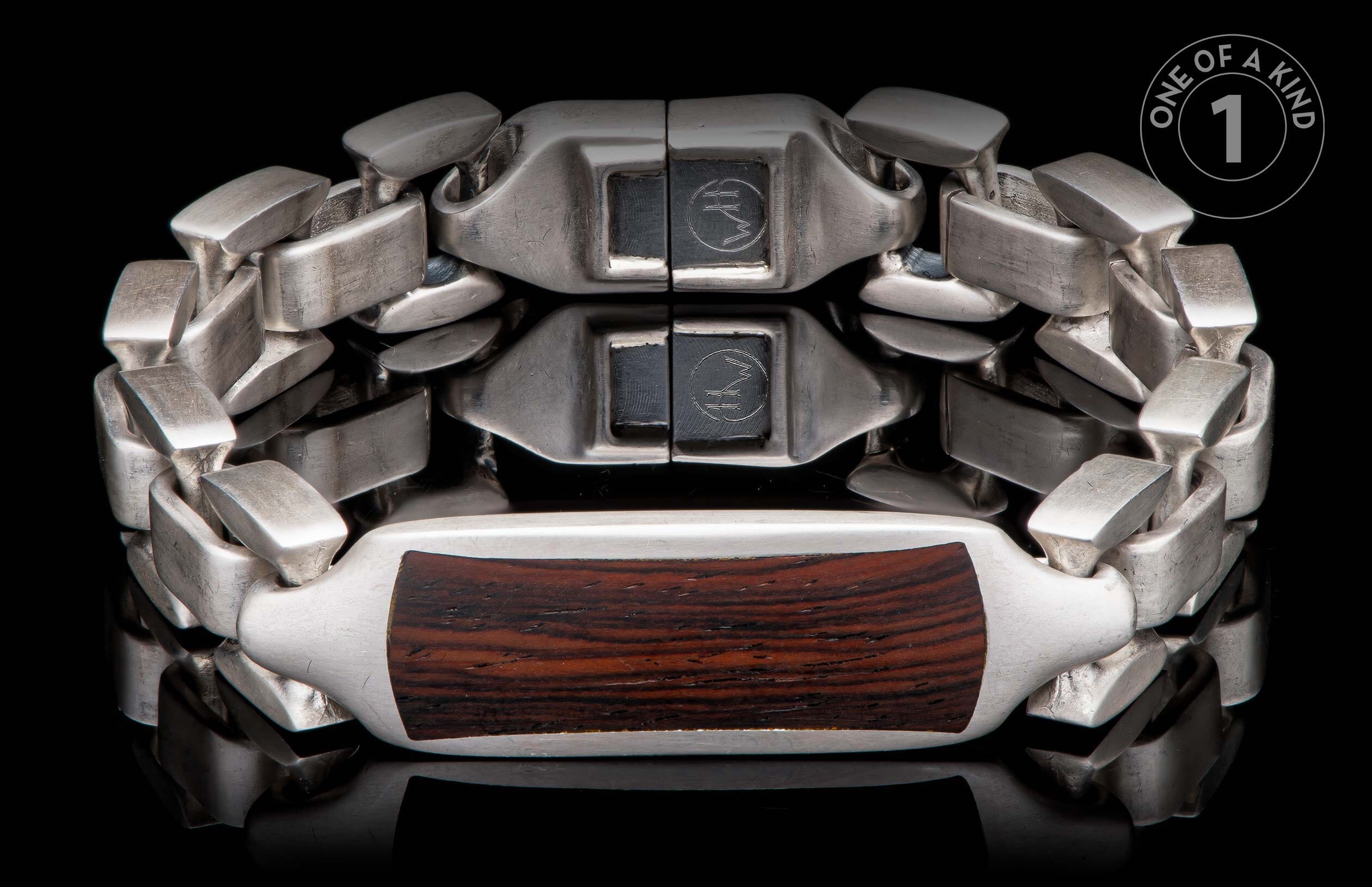 Silver bracelet with dark wood inlay, featuring interlocking links and a reflective black background.