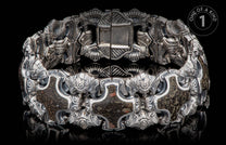 Ornate silver bracelet with intricate, dark, mottled stone inlays and a prominent, partly open clasp.