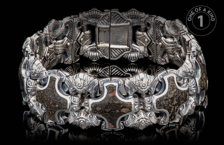 Ornate silver bracelet with intricate, dark, mottled stone inlays and a prominent, partly open clasp.