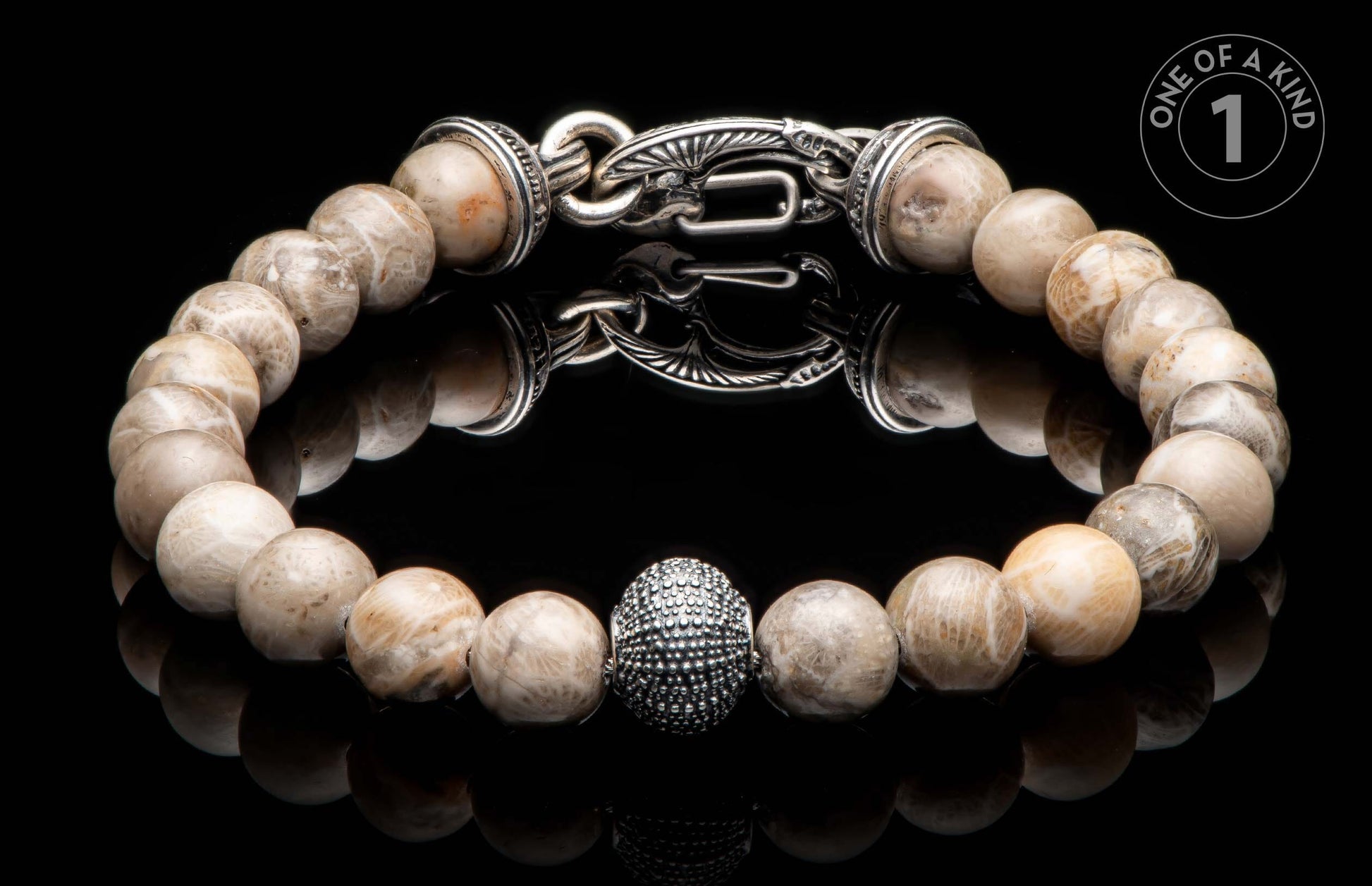 Light-toned natural stone beaded bracelet with an ornate silver clasp, textured oval bead, and "ONE OF A KIND" graphic.