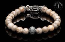 Light-toned natural stone beaded bracelet with an ornate silver clasp, textured oval bead, and "ONE OF A KIND" graphic.