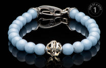 Light blue beaded bracelet featuring a silver-tone ornate clasp and an intricate central charm, reflected on a dark surface.