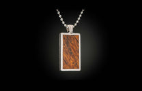 Rectangular pendant with a reddish-brown wood inlay featuring diagonal grain, set in a textured silver-tone metal frame, suspended from a ball chain.