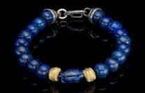 Lapis lazuli beaded bracelet with gold pyrite flecks, a large blue barrel bead, ribbed gold beads, and a carved silver clasp.