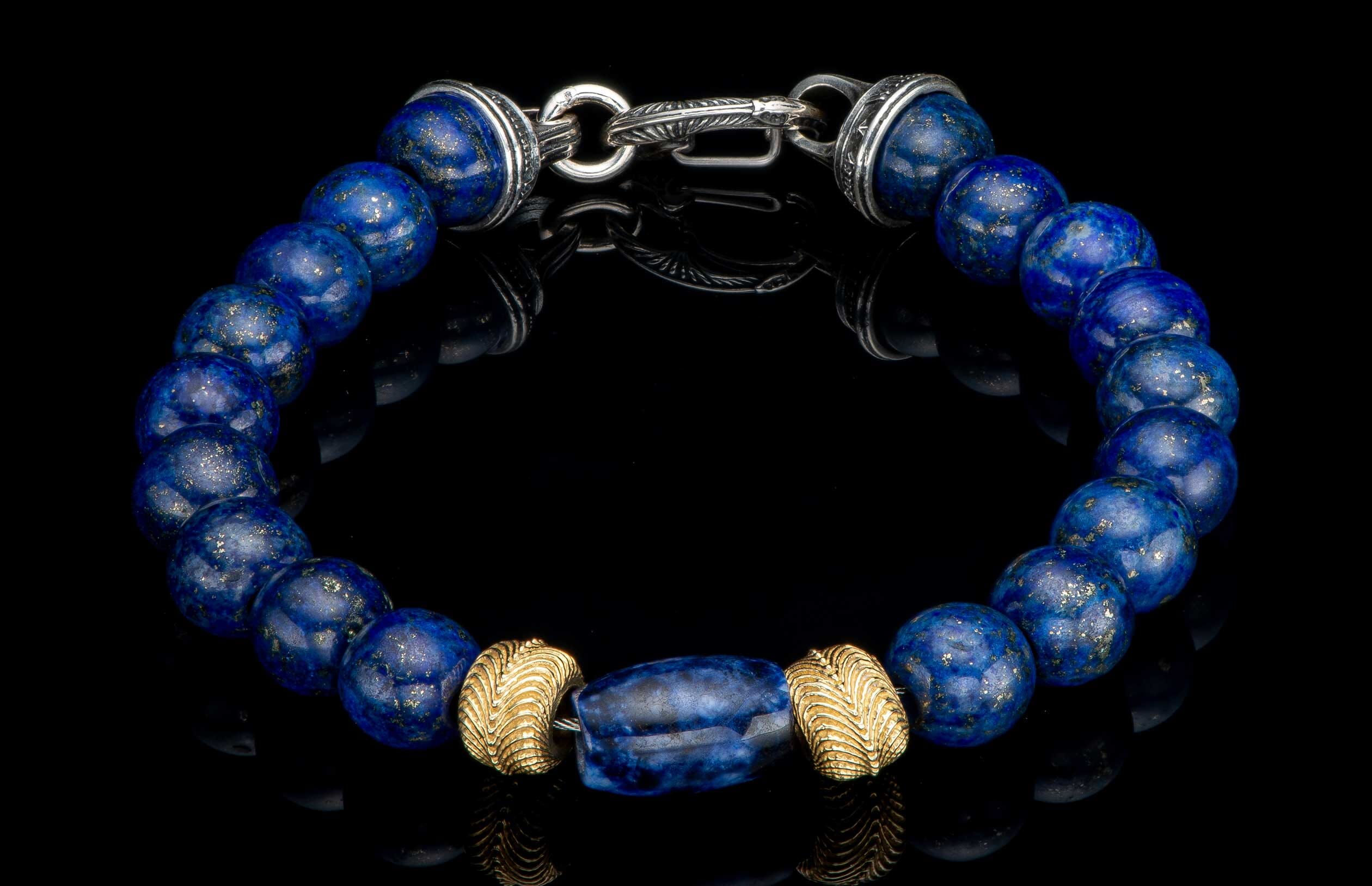 Lapis lazuli beaded bracelet with gold pyrite flecks, a large blue barrel bead, ribbed gold beads, and a carved silver clasp.