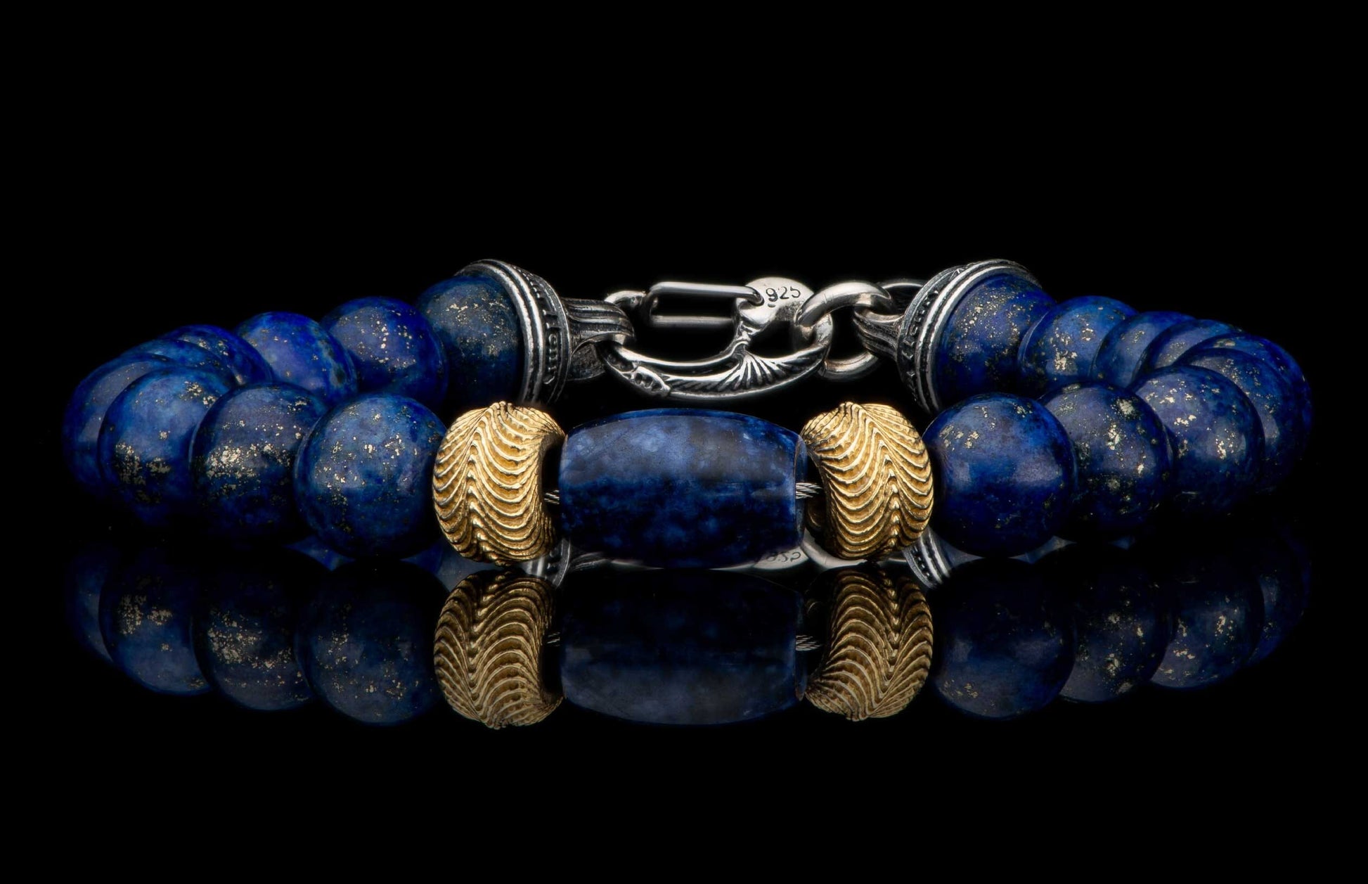 Deep blue lapis lazuli beaded bracelet with gold flecks, textured gold spacers, and a detailed silver clasp, reflecting on black.