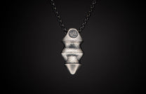 Silver-toned textured pendant displaying a 'WH' logo, geometric ridged body, pointed tip, and a dark chain.