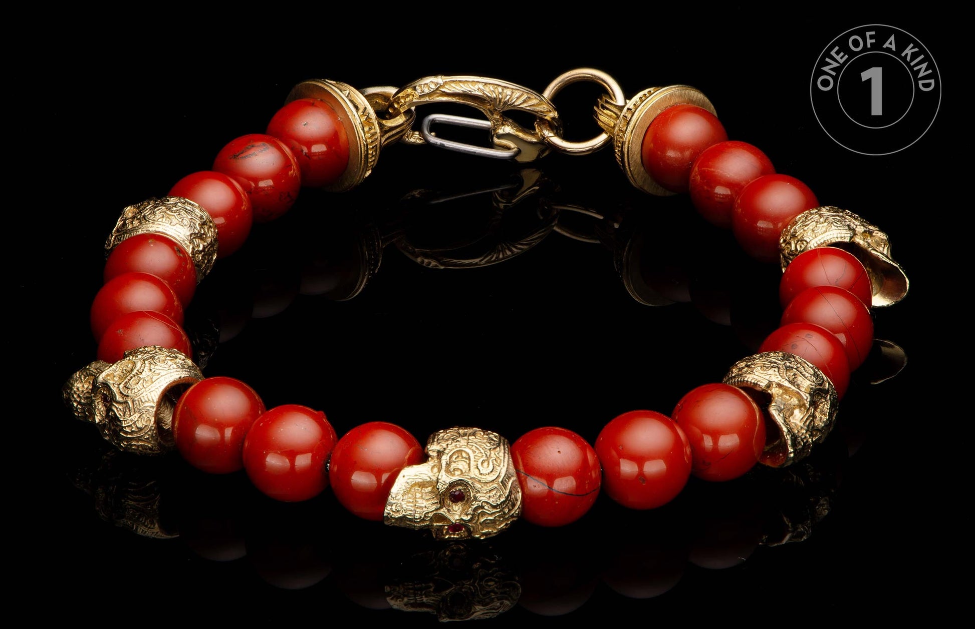 Red beaded bracelet with ornate gold-tone skull beads featuring small red gemstones and an intricate clasp.