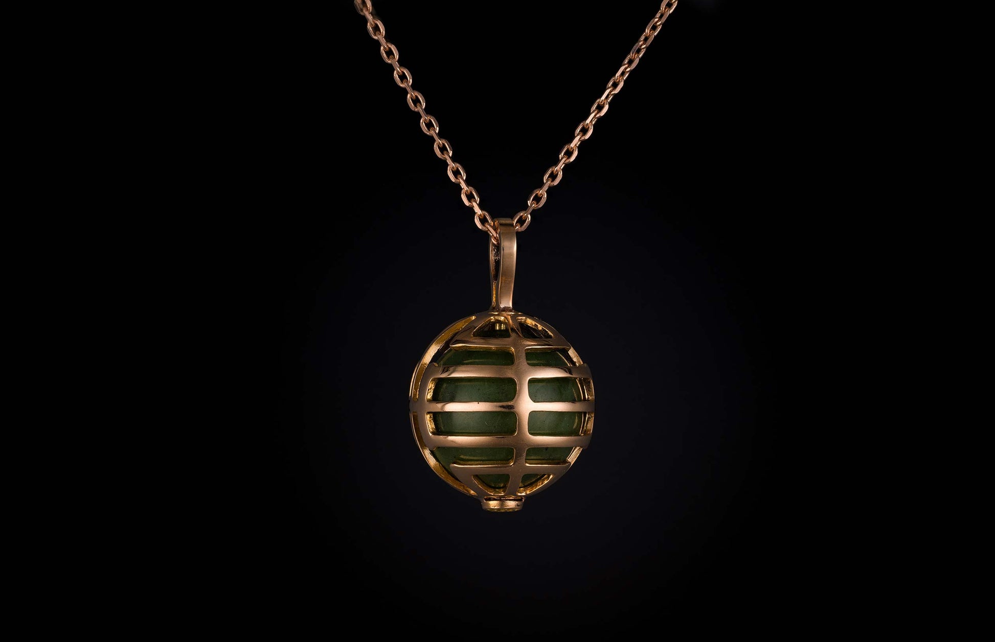 William Henry necklace with green stone encased within a rose gold spherical cage.